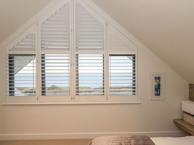 A bedroom with a window and shutters at Praa Waves in Penzance
