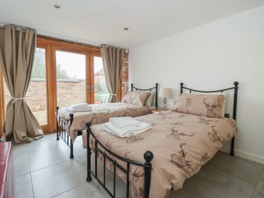 A bedroom with two beds and sliding doors at Pillar Barn Driffield