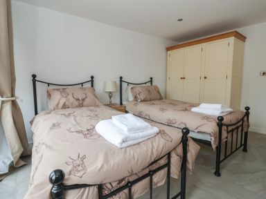 A bedroom with two single beds and a wardrobe at Pillar Barn in Driffield