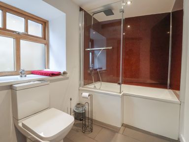 A bathroom with a toilet and a shower over the bathtub at Pillar Barn in Driffield