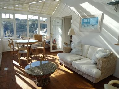 A conservatory with a dining table and chairs, a couch, and a coffee table at Mount Pleasant in Padstow