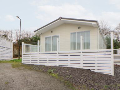 A cabin with white fencing and a gravel pathway at Beechwood Lodge in 