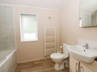 A bathroom with a bathtub, toilet, and washbasin at Beechwood Lodge