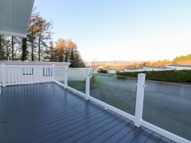 A deck with glass railing overlooking the landscape at Beechwood Lodge 