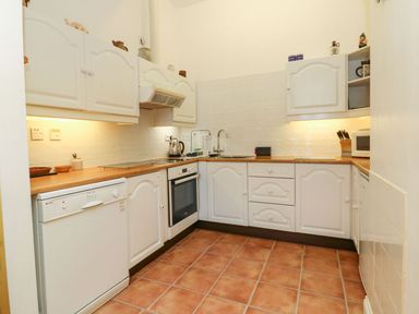 A kitchen with cabinets, an oven, a sink, and a dishwasher at Val's Seaview in Ilfracombe