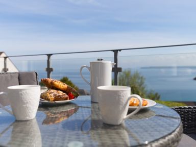 A table with cups and a teapot on a balcony at 2 Remera St Ives