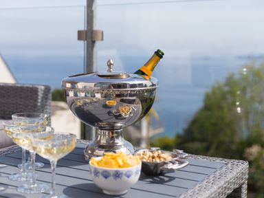 A champagne cooler with glasses and snacks on a table at 2 Remera in St Ives