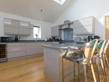 A kitchen with modern appliances and bar stools at 2 Remera St Ives