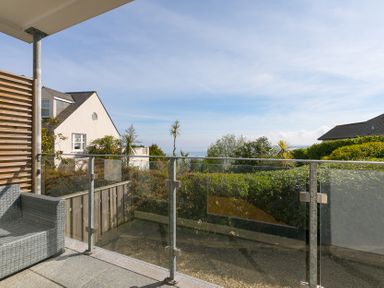 A balcony with a glass railing and a couch at 2 Remera in St Ives
