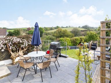A garden with a table and chairs and a barbecue grill at Orchard View in St. Austell