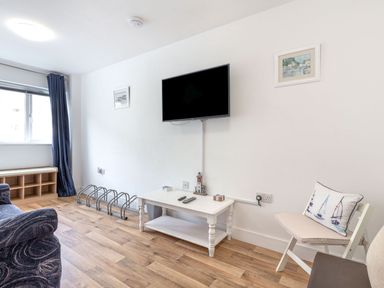 A living room with a television and shelf at Orchard View in St. Austell