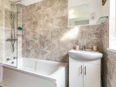A bathroom featuring a bathtub, shower, sink, and mirror at Orchard View, St. Austell