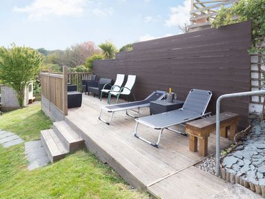An outdoor area with lounge chairs and a table at Orchard View in St. Austell