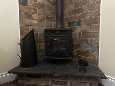 A wood stove with a flue pipe and tools on slate hearth at The Rocks in Newry