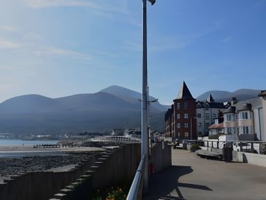 A view of a seaside pathway with buildings and mountains at The Rocks in Newry