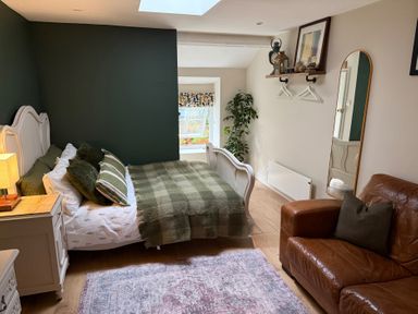 A bedroom with a bed and brown couch at Studio Apartment at High Dyke Farm, Cockermouth