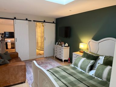 A bedroom with a bed, sofa, television, and dresser at Studio Apartment at High Dyke Farm Cockermouth