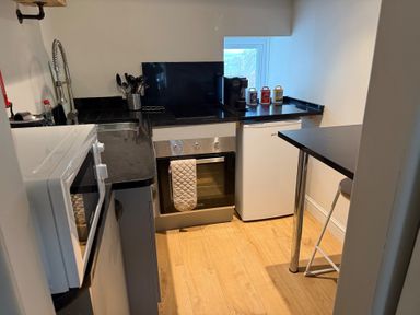 A kitchen with stove, oven, sink, and refrigerator at Studio Apartment at High Dyke Farm in Cockermouth