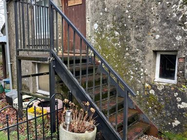 A staircase leading to a door next to a textured wall at Studio Apartment at High Dyke Farm Cockermouth