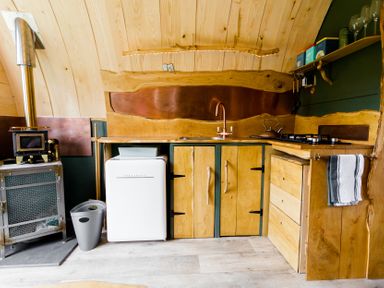 A kitchen with wooden cabinets and appliances at Glamping pod-Luxury Glamping Retreat in Battle