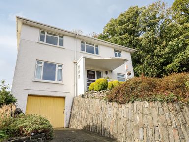 A house with a garage and stone wall at Tymelyn in Aberystwyth
