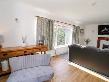 A living room with a sofa and a window at Tymelyn in Aberystwyth