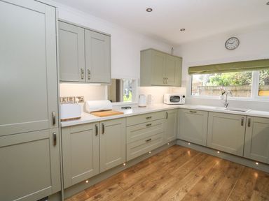 A kitchen with cabinets, sink, and appliances at Tymelyn Aberystwyth