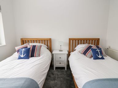 A bedroom with twin beds and a bedside table at Tymelyn in Aberystwyth