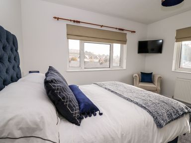 A bedroom with a bed and television at Tymelyn Aberystwyth