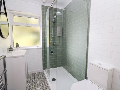 A bathroom with a shower, toilet, and sink at Tymelyn in Aberystwyth