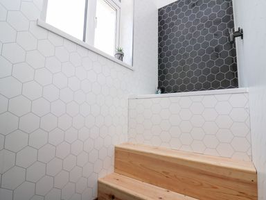 A bathroom with a shower and stairs at Tymelyn, Aberystwyth