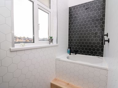 A bathroom with a bathtub and window at Tymelyn in Aberystwyth
