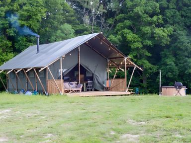 A tent with a wooden deck and seating area at Badger - Luxury Glamping Retreat in Battle