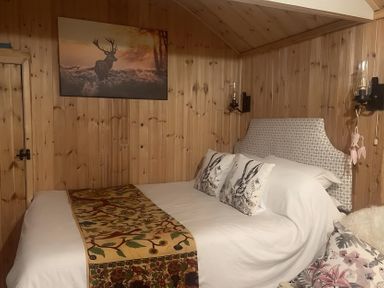 A bedroom with a bed, bedside lamps and wall art at Tylands in Camelford