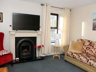 A living room with a television, fireplace, sofa, and armchair at The Farmhouse in Omagh