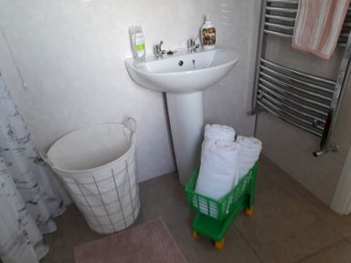 A bathroom with a sink, towels on a rack, and a laundry basket at The Farmhouse in Omagh