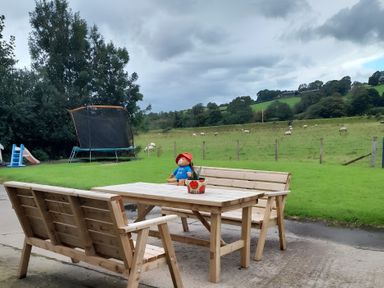 An outdoor seating area with a table and benches at The Farmhouse in Omagh