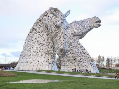 A horse sculpture surrounded by grass and people at The Kelpies in Falkirk