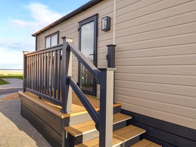 Steps leading to a door with a railing at Paws By The Sea in Norwich