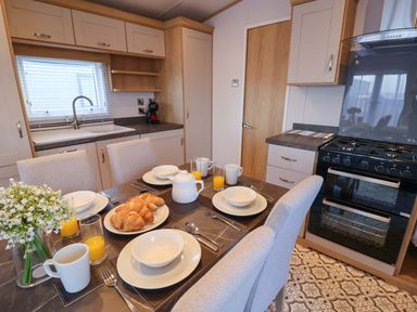 A kitchen with a dining table set for breakfast at Paws By The Sea in Norwich