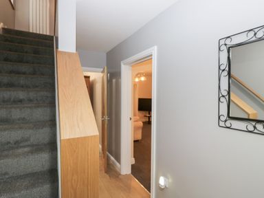 A hallway with staircase and mirror at Mables in Wigton