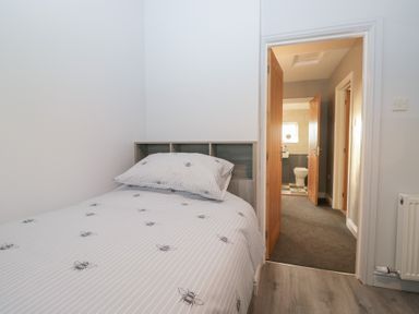 A bedroom with a bed and doors leading to bathroom at Mables in Wigton