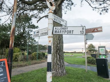 A signpost indicating directions and distances to various locations near a park