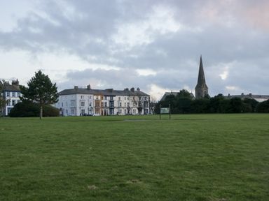 A park with buildings and a church in the background at Mables in Wigton