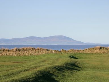 A landscape with grass, ocean, and mountains at Mables in Wigton
