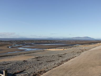 A beach with a river flowing and mountains in the background at Mables in Wigton