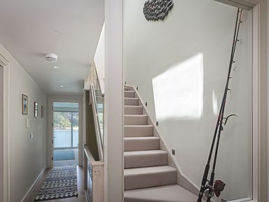 A hallway with a staircase and fishing rod at Villa 8, Estura Salcombe