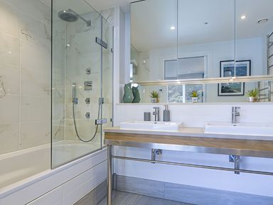 A bathroom with a shower, bathtub and two sinks at Villa 8, Estura in Salcombe