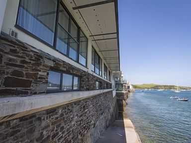 A waterfront view of a building with windows and boats at Villa 8, Estura in Salcombe