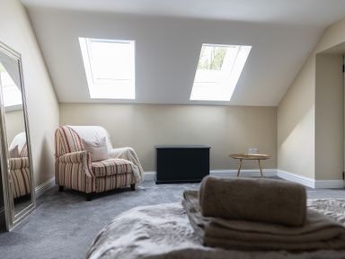 A bedroom with a striped armchair and a mirror at 6 Front Street